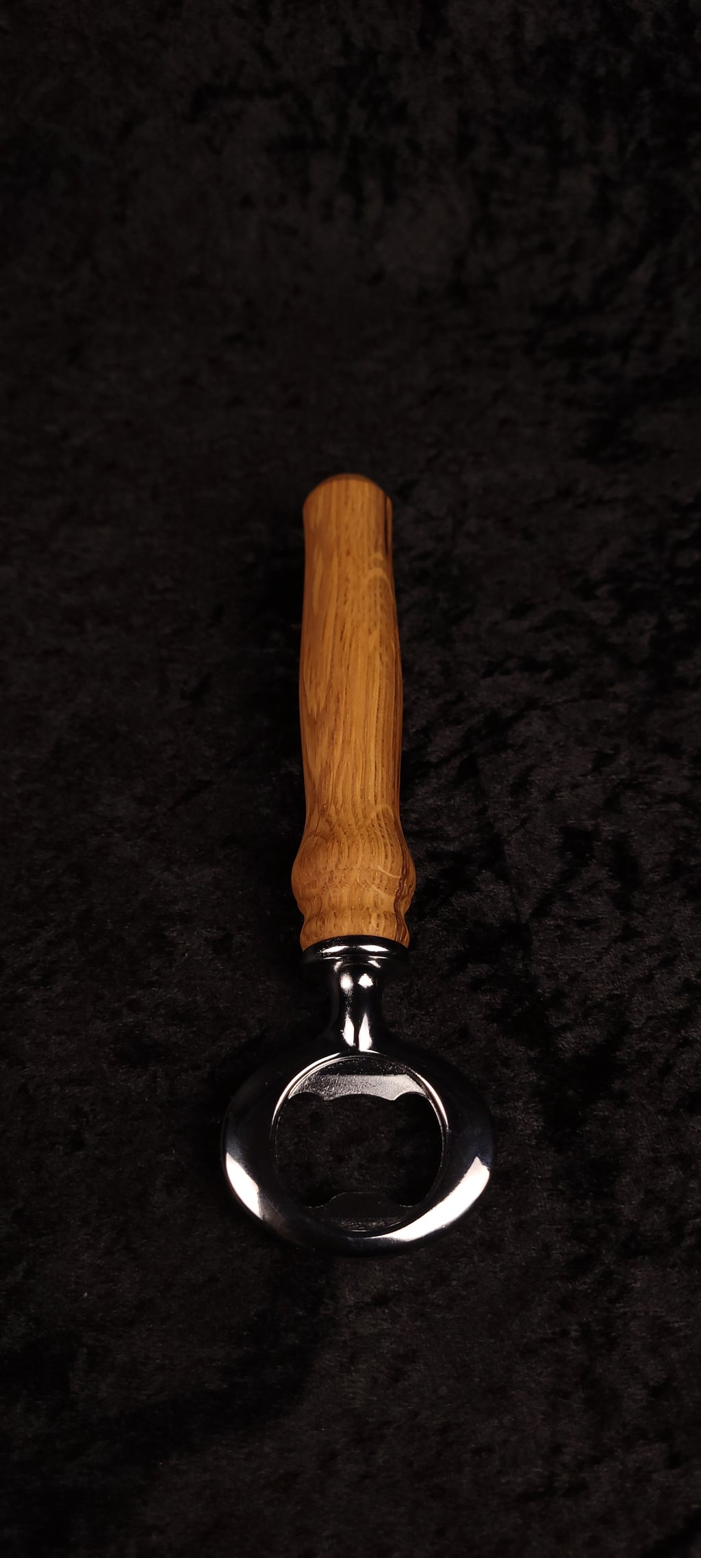 Oak wood bottle opener on dark background, side view