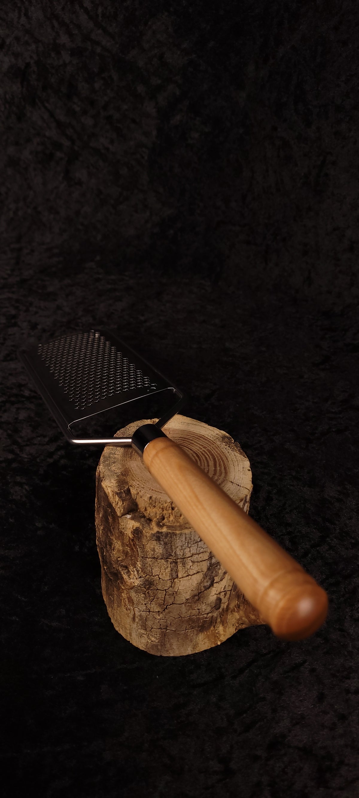 Handcrafted curly maple handle grater resting on wood round