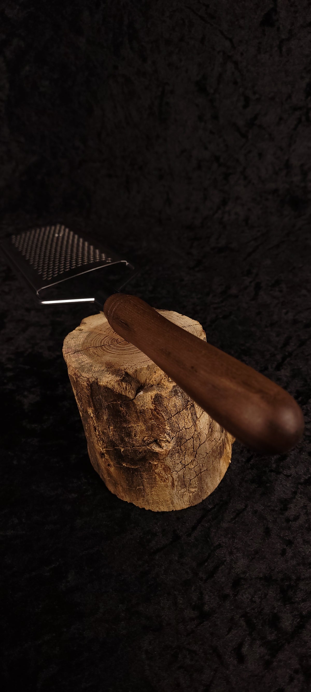 Walnut rasp grater resting on wood round