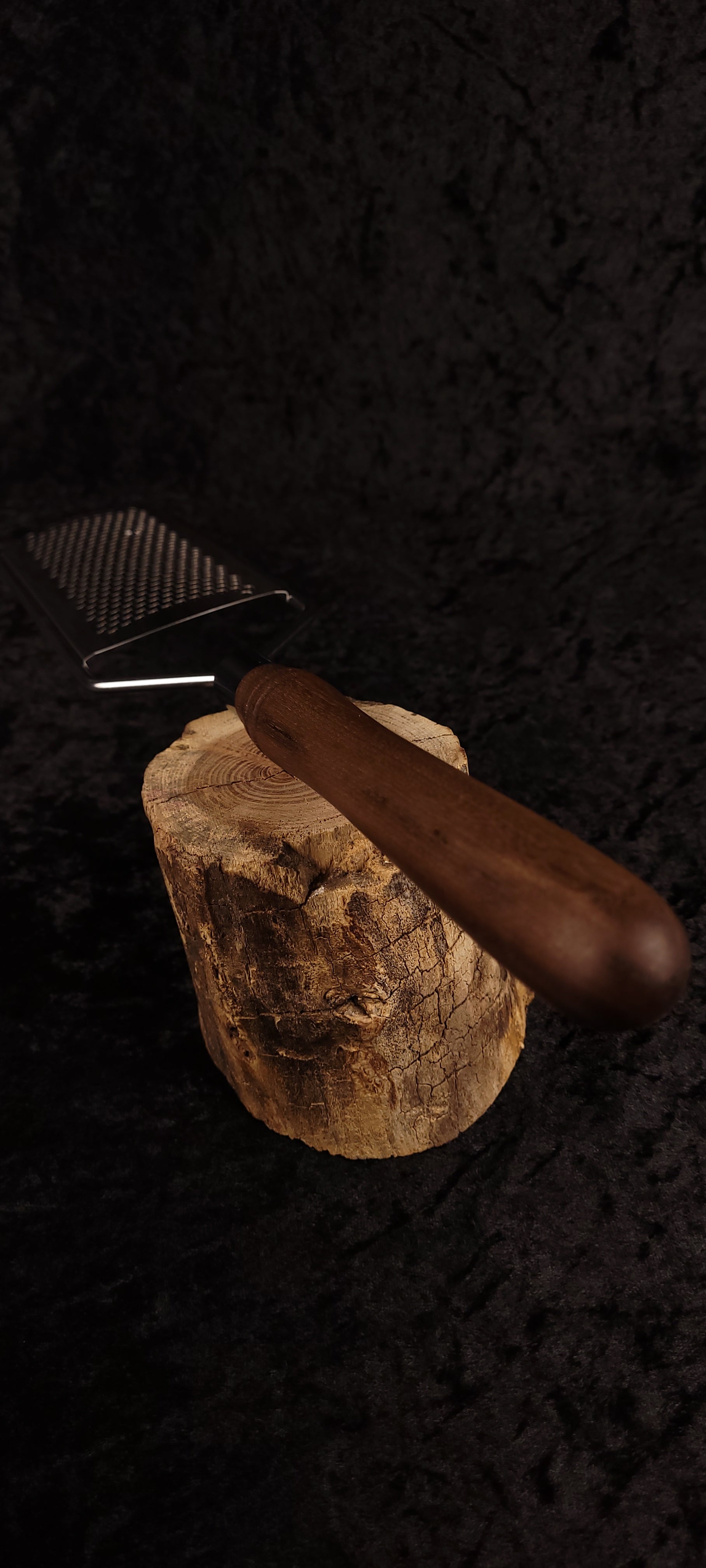 Walnut rasp grater resting on wood round