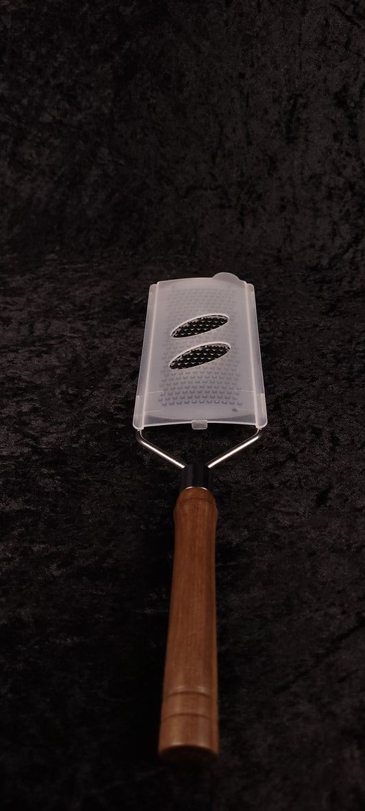 Handcrafted walnut rasp grater with plastic guard, top-down view