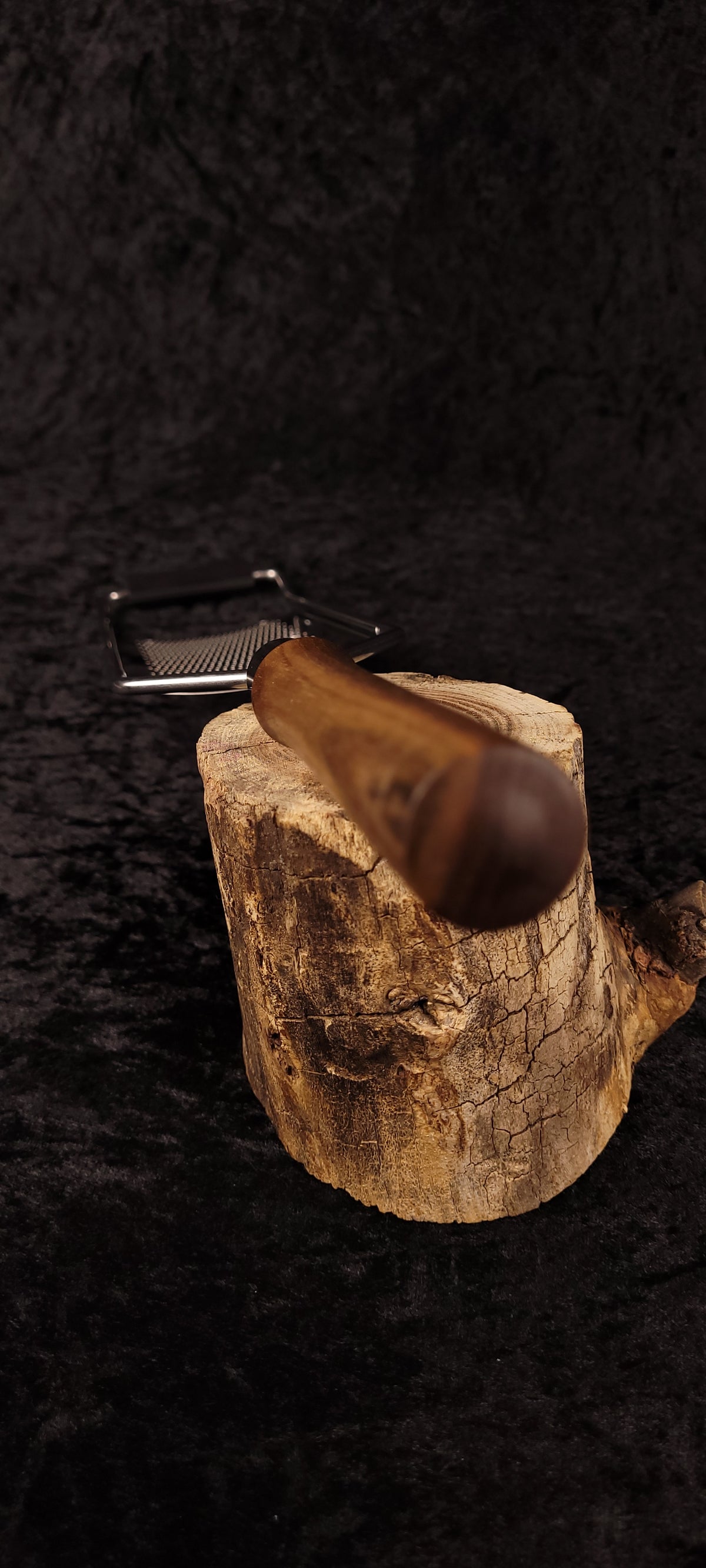Walnut rasp grater on wood round, alternate angle showing ball end