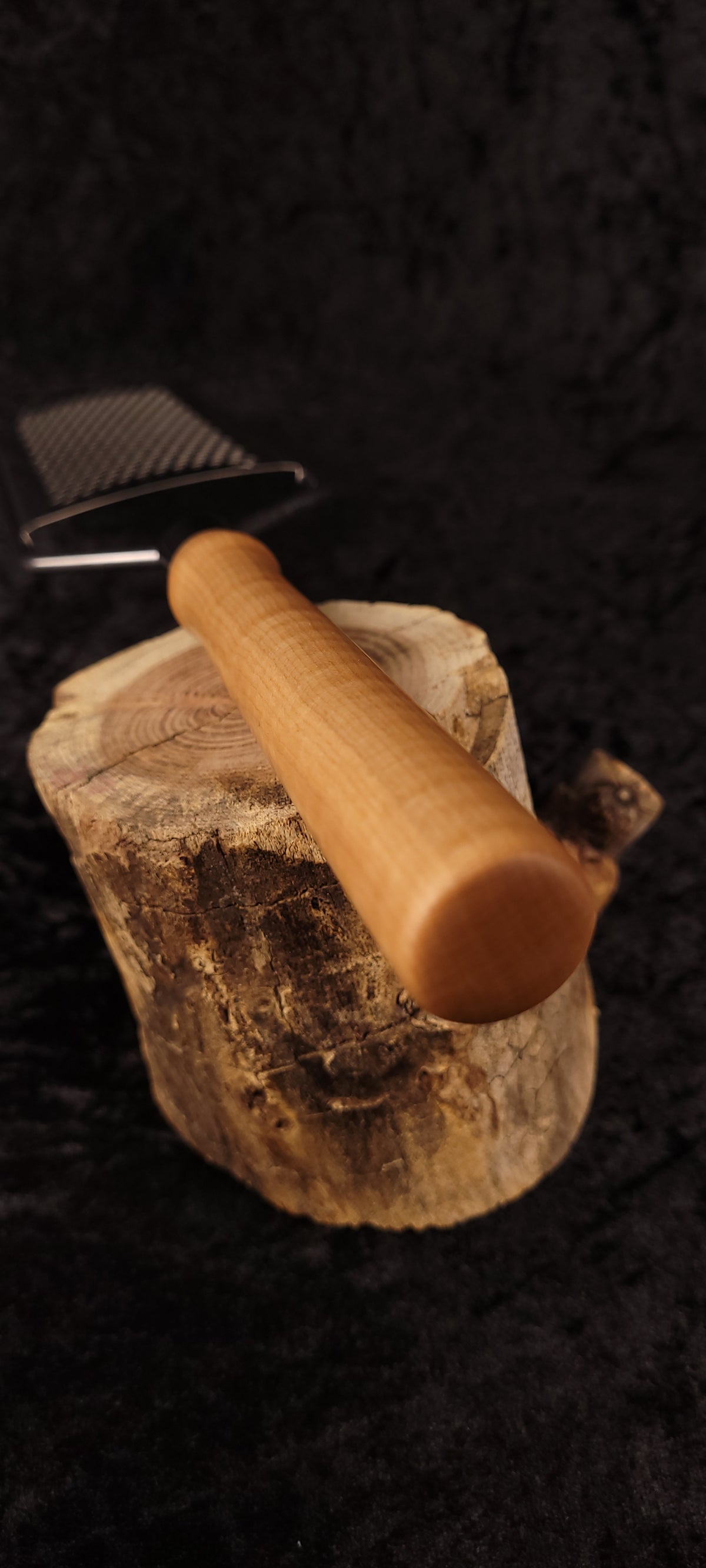 Curly maple rasp grater handle resting on wood round, side view