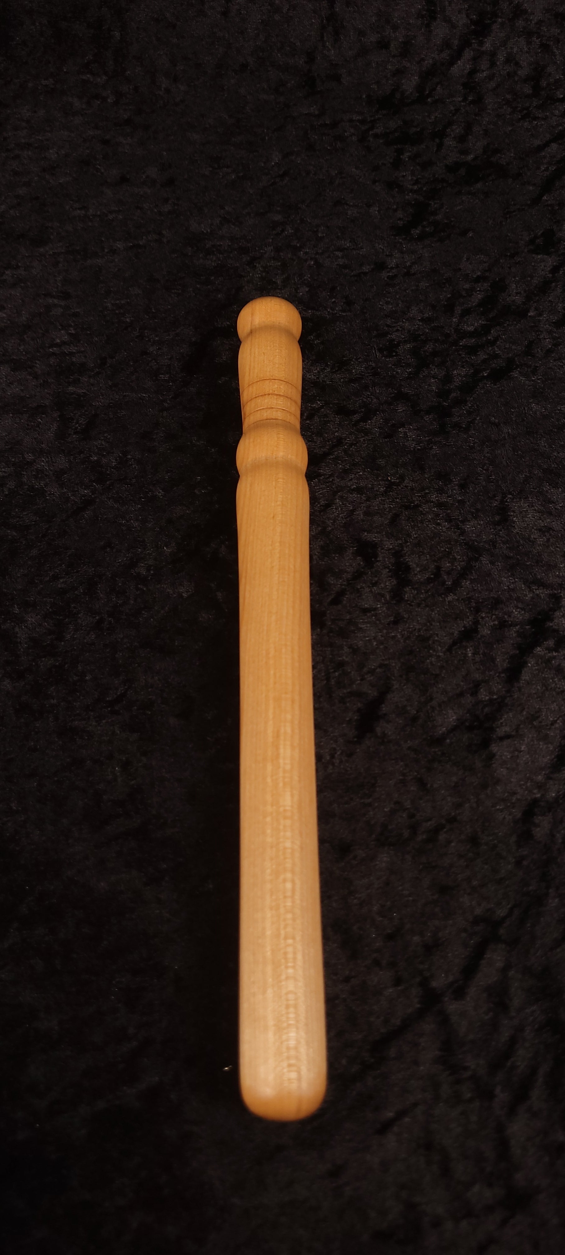 Curly maple spurtle full length top-down view on dark background