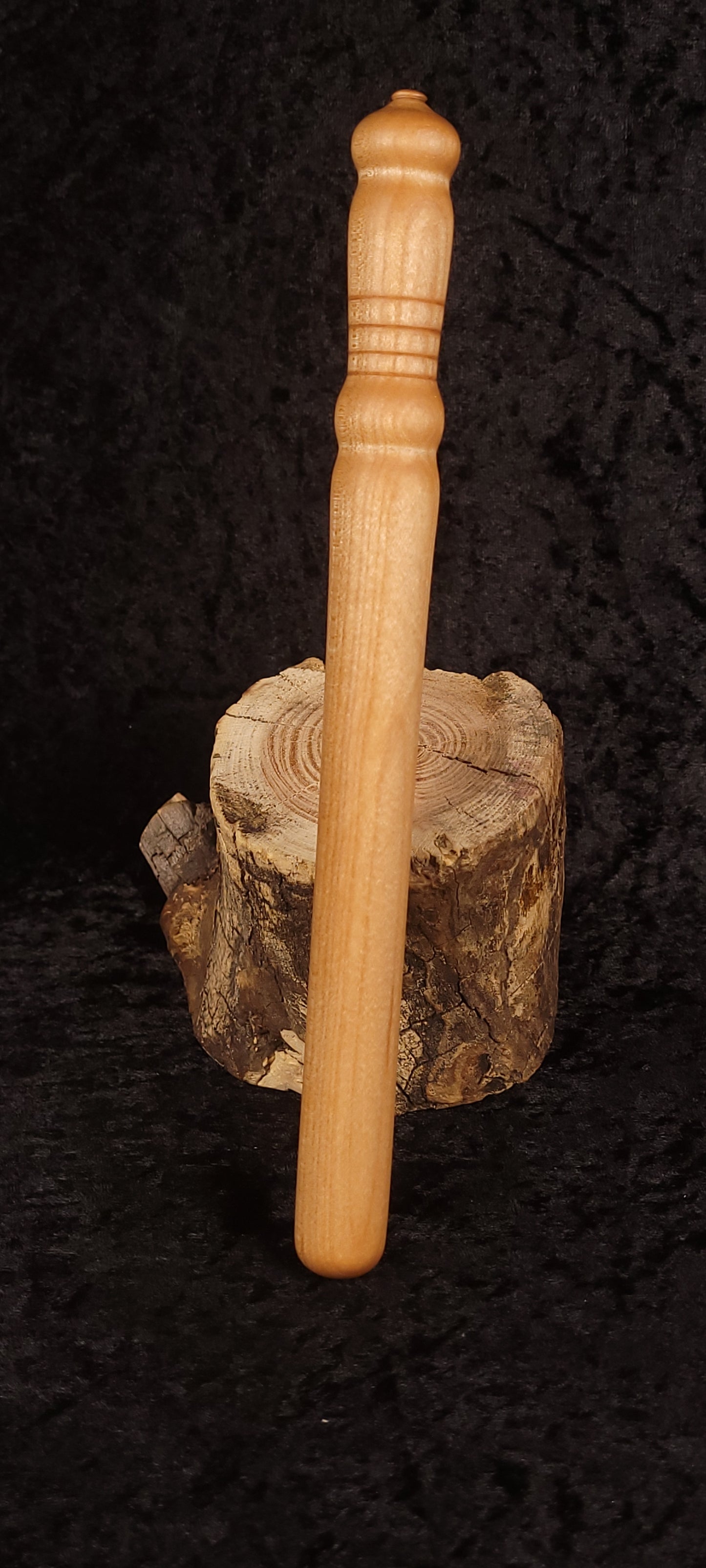 Handcrafted curly maple spurtle standing on wood round, front view