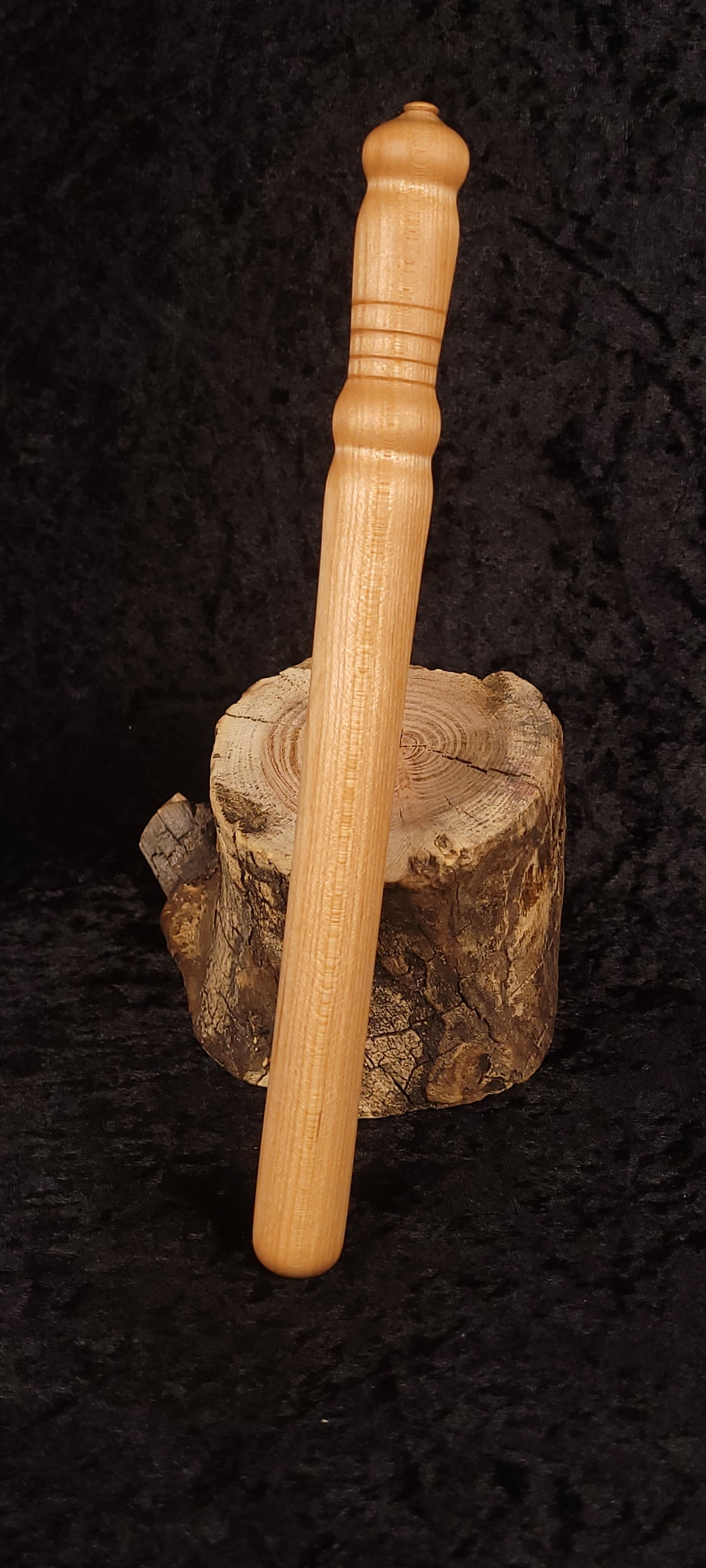 Curly maple spurtle on wood round, side view showing taper