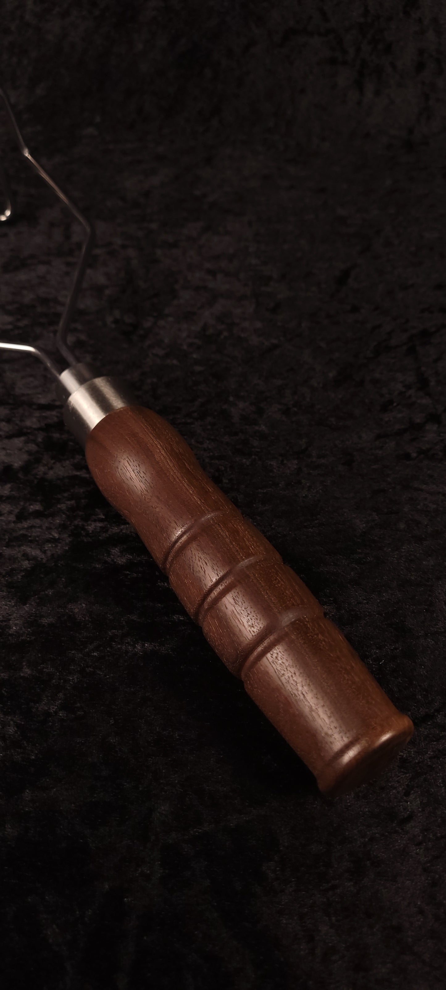 Handcrafted walnut potato masher top-down view showing wire head