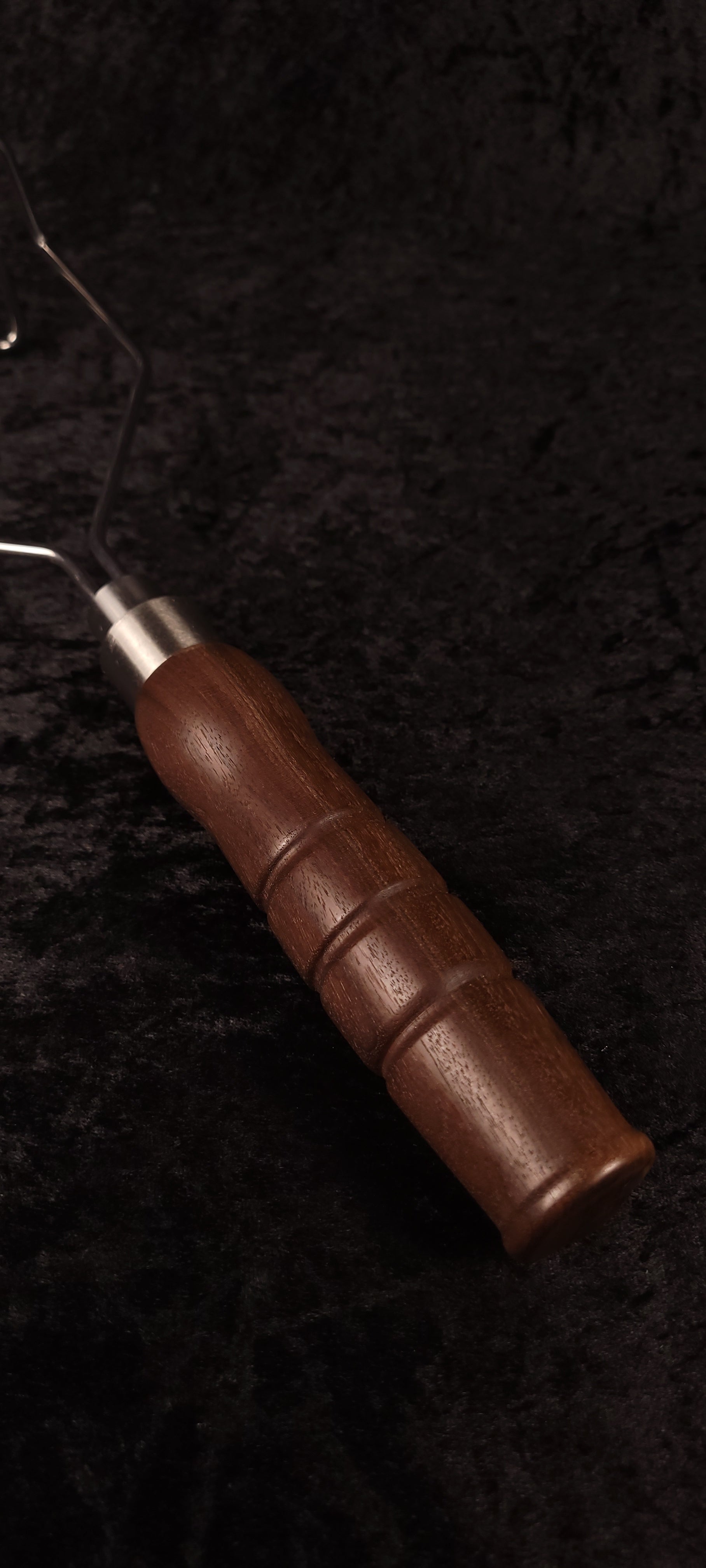 Handcrafted walnut potato masher top-down view showing wire head
